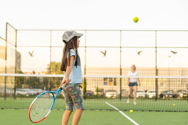 Portrait of a cute little girl playing tennis - Valokuva, kuva