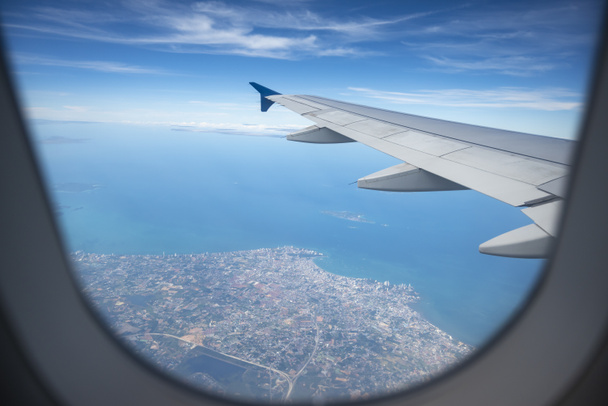 Flugzeugflügel vor wunderschönem blauen Himmel und Wolkenhintergrund. Während des Fluges über dem Meer von Pattaya in Thailand. Tragfläche eines Flugzeugs, das aus dem Fenster schaut. - Foto, Bild