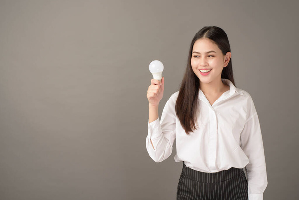 Beautiful intelligent woman is holding light bulb in studio  - Fotografie, Obrázek