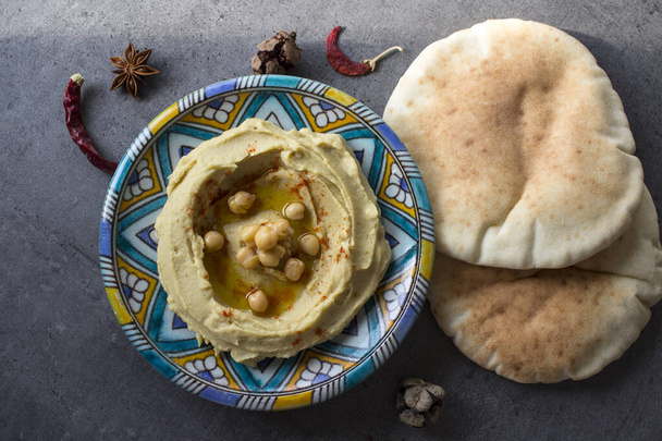 Vista superior de la foto del plato de hummus. Comida del Medio Oriente. Concepto de alimentación saludable. Fondo gris con espacio de copia. - Foto, Imagen