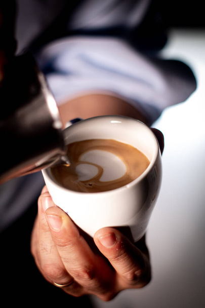 Деталь рук чоловіка, що подає чашку кави Молоко має гарну форму
. - Фото, зображення