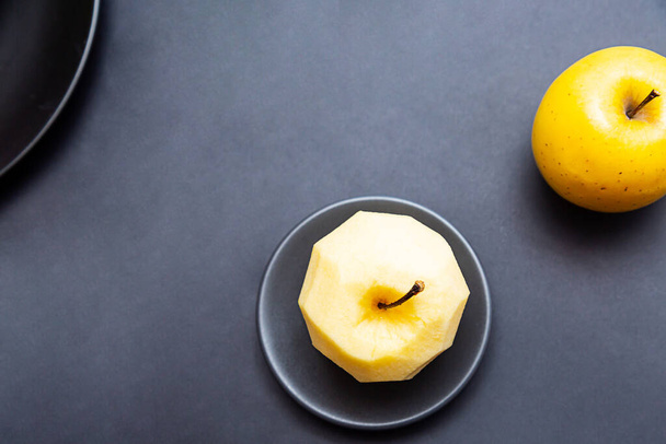 Maçã amarela e maçã sem casca em um fundo escuro. Conceito de alimentação saudável com espaço de cópia - Foto, Imagem