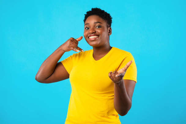 Plus-Size africano donna gesturing chiamami su sfondo blu - Foto, immagini