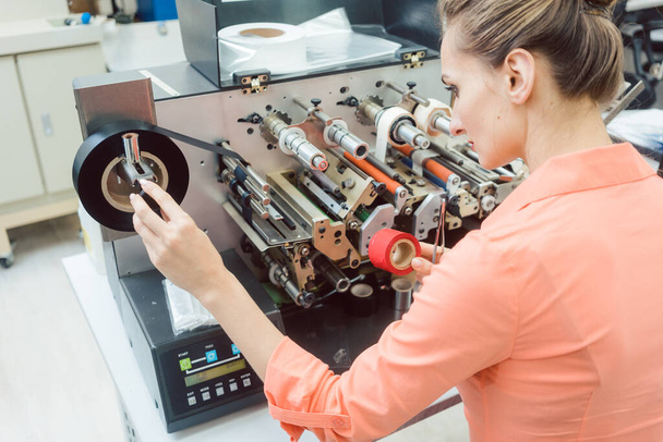 Mujer trabajadora poniendo nuevas etiquetas en la máquina de impresión - Foto, Imagen