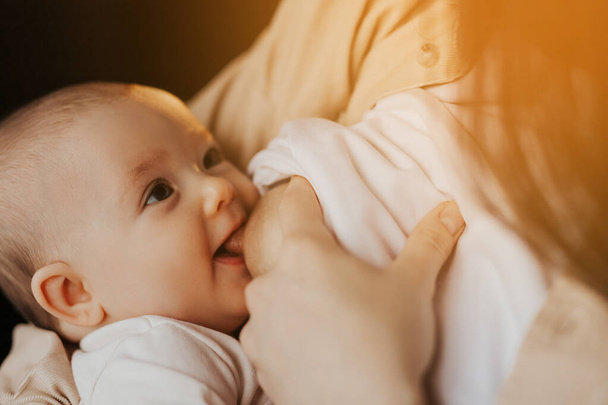 close up portrait of a child breastfeeding. mother breastfeeding smiling baby in bed dark night by lamp light - Zdjęcie, obraz