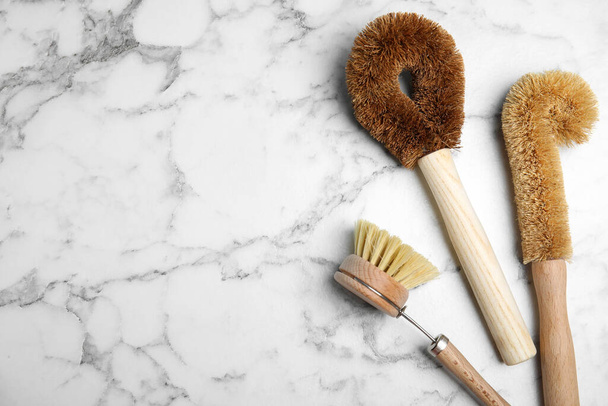 Cleaning brushes on white marble table, flat lay with space for text. Dish washing supplies - Foto, imagen