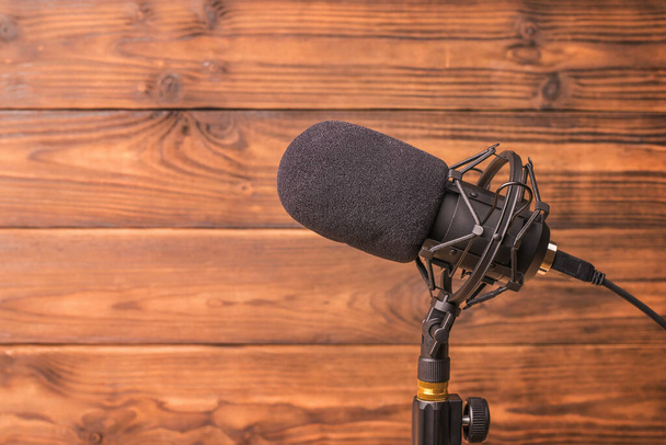 Modern microphone on a stand on a wooden background. Sound recording equipment. - Photo, Image