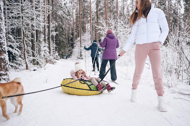 Madre feliz y niña linda en ropa interior de color rosa cálido caminar divertirse paseos inflable tubo de nieve en nieve blanca fría bosque de invierno al aire libre. Deportes de familia actividades de vacaciones - Foto, imagen