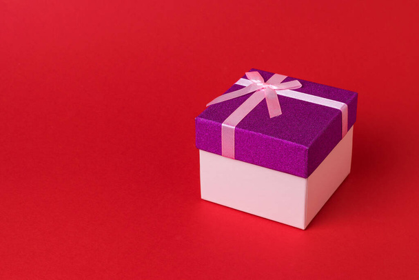 Stylish beautiful gift box with a bow on a red background. A holiday gift. - Foto, immagini