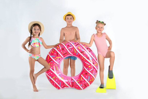 Cute little children in beachwear with bright inflatable ring on white background - Fotoğraf, Görsel