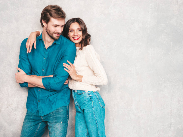 Portrait of smiling beautiful woman with red lips and her handsome boyfriend. Happy cheerful family posing in studio near gray wall.Valentine's Day. Models hugging. Concept of love - Foto, Imagen