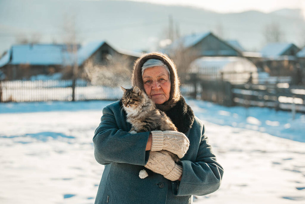 Rosyjska babcia trzyma kotka w ramionach, wioska, Syberia, zima - Zdjęcie, obraz
