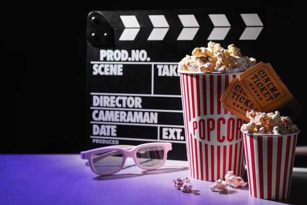 Delicious popcorn, tickets, glasses and clapper on table - Фото, изображение