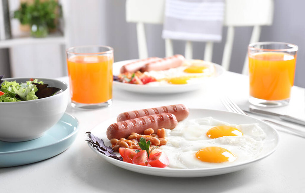 Delicious breakfast with fried eggs and sausages served on white table - Foto, immagini