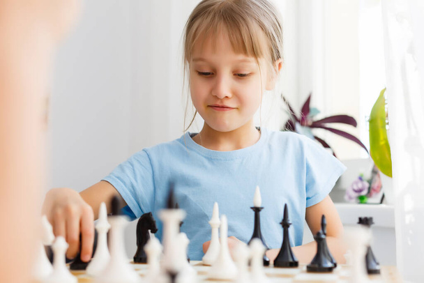 Маленькая девочка играет в шахматы за столом - Фото, изображение