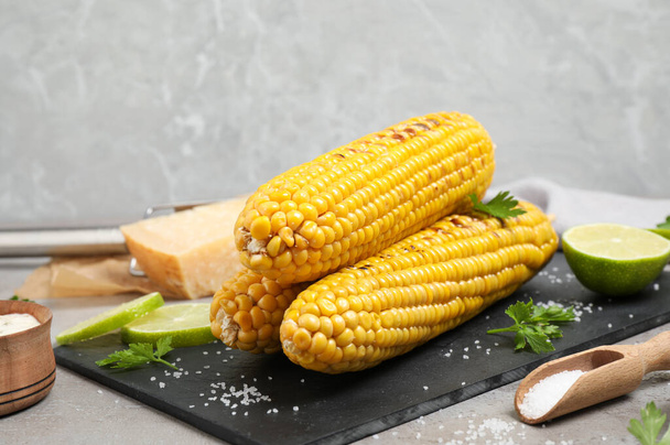 Delicious grilled corn cobs on grey table - Fotoğraf, Görsel