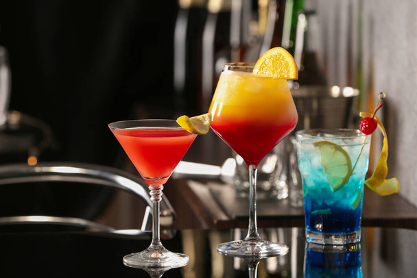 Different delicious cocktails on black table in bar - Fotó, kép