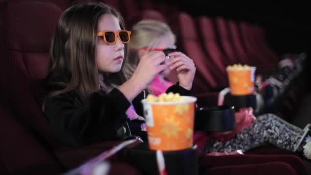 Klein meisje alleen in de bioscoop kijkt naar het bioscoopscherm. Naar een kinderfilm of tekenfilm kijken in de bioscoop. - Video