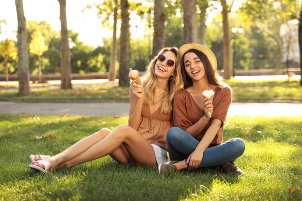 Young women with ice cream spending time together outdoors - Фото, изображение