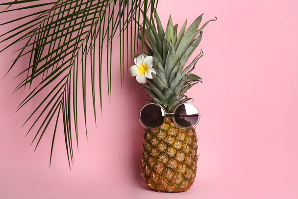 Pineapple with sunglasses, plumeria flower and palm tree leaves on pink background. Creative concept - Foto, immagini