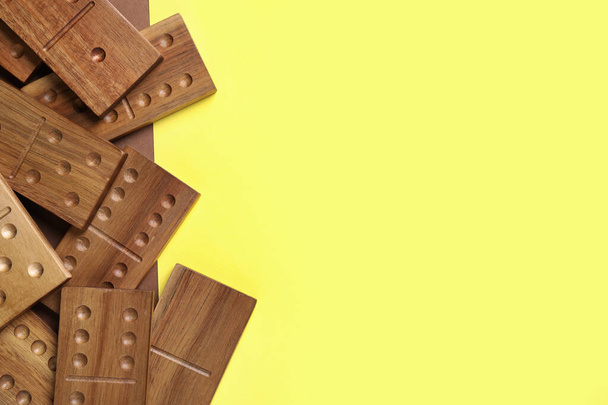 Wooden domino tiles on yellow background, flat lay. Space for text - Фото, изображение