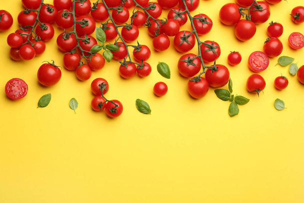Fresh cherry tomatoes and basil leaves on yellow background, flat lay. Space for text - Fotoğraf, Görsel