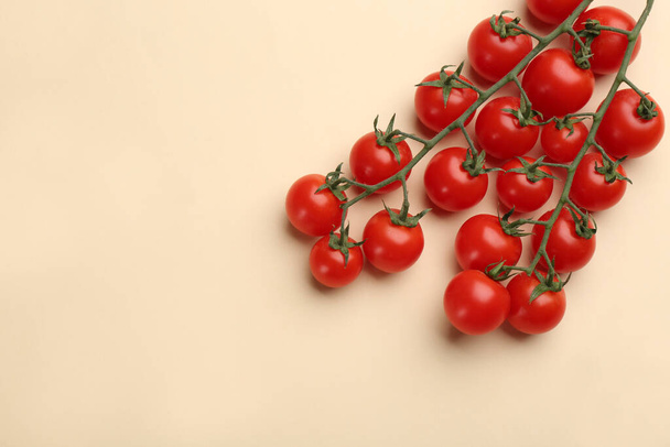 Branches with fresh cherry tomatoes on beige background, flat lay. Space for text - Photo, Image