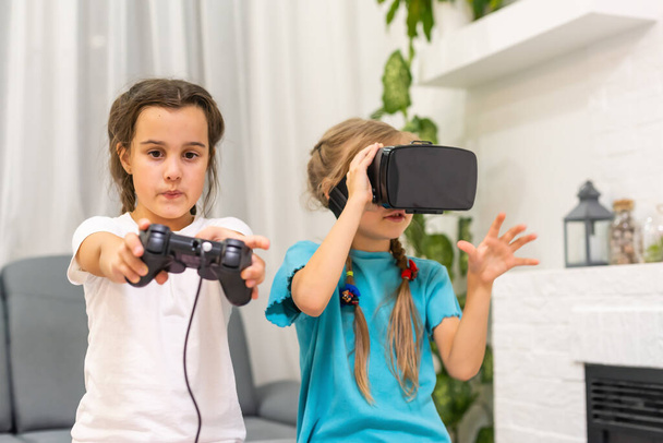 twee kleine meisjes met een bril van virtual reality headset. concept van moderne technologieën - Foto, afbeelding