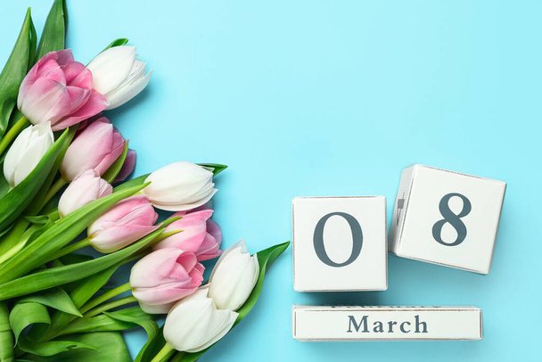 Houten blokkenkalender met datum 8 maart en tulpen op lichtblauwe achtergrond, vlak gelegd. Ruimte voor tekst - Foto, afbeelding