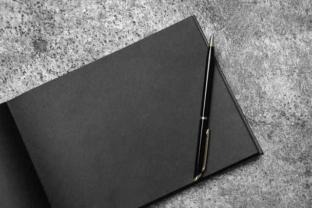 Open sketchbook with black pages and pen on grey stone table, top view - Photo, image