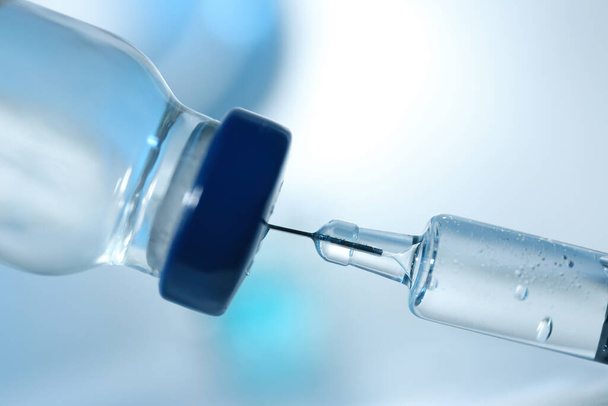 Filling syringe with COVID-19 vaccine on blurred background, closeup - Foto, afbeelding