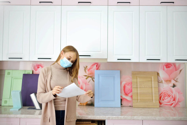 bizneswoman projektantka w masce zatwierdza projekt mebli szafy zdalnie. Planowanie kuchni. Koncepcja sprzedaży podczas pandemii i wirusa - Zdjęcie, obraz