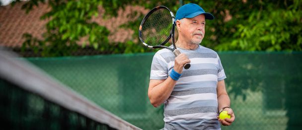 Portrait d'un aîné actif jouant au tennis à l'extérieur, pensionné en forme - Photo, image