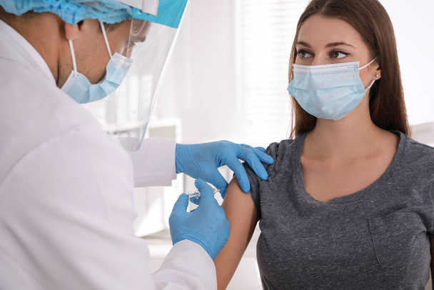 Doctor vaccinating young woman against Covid-19 in clinic - Photo, image