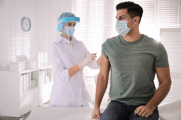 Doctor vaccinating man against Covid-19 in clinic - Фото, зображення
