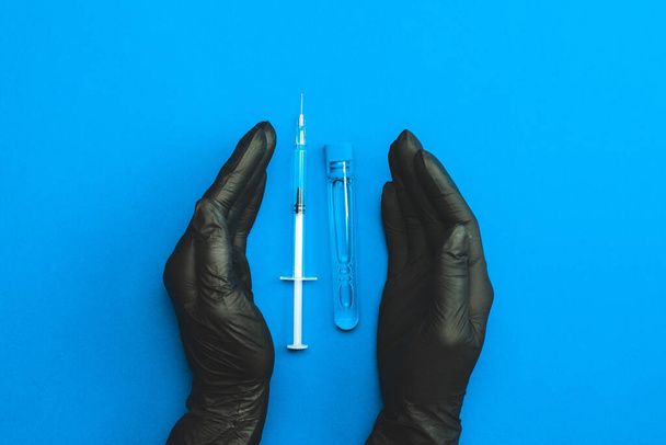 Шприц ізольований. Рука лікаря в медичній рукавичці тримає шприц голкою для захисту вірусу грипу та коронавірусу. Вакцина від ковадла ізольована на синьому. Концепція боротьби з вірусом ковадла-19
 - Фото, зображення
