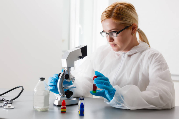 Eine schöne medizinische oder wissenschaftliche Forscherin mit ihrem Mikroskop in einem Labor. - Foto, Bild
