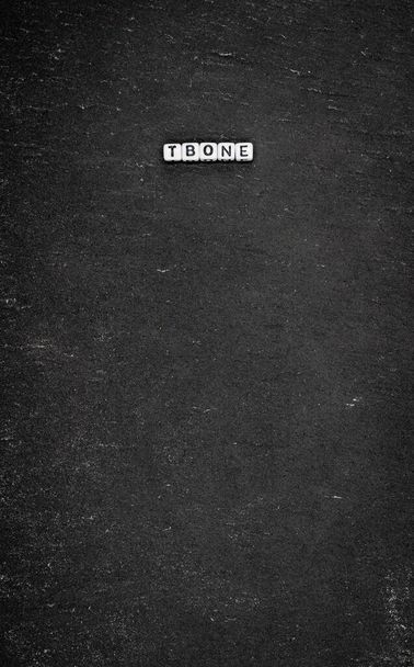 Woord tbone op zwarte steen achtergrond - Foto, afbeelding