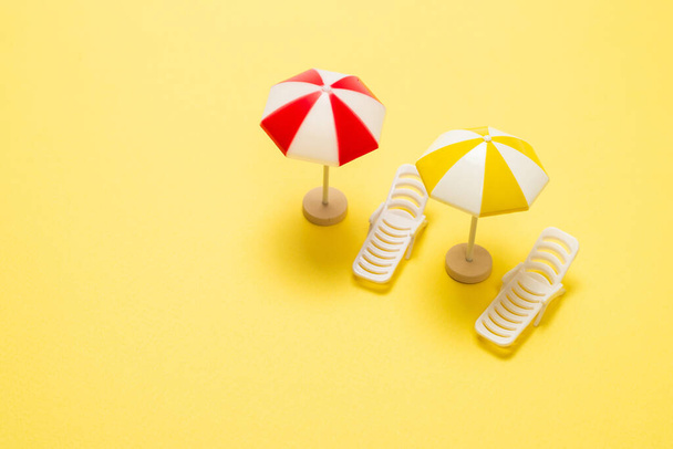 Dos tumbonas y un paraguas rojo sobre fondo amarillo. Copiar espacio. - Foto, imagen