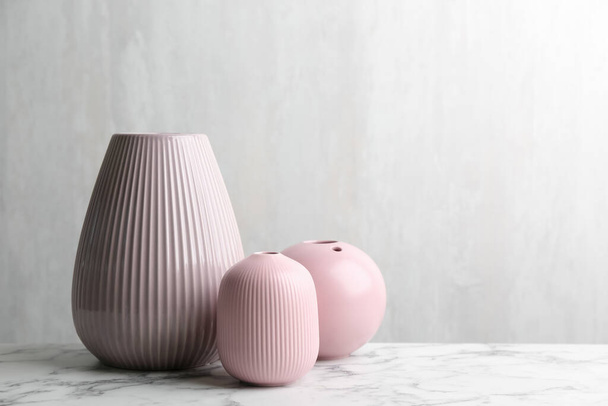 Stylish empty ceramic vases on white marble table, space for text - Fotó, kép