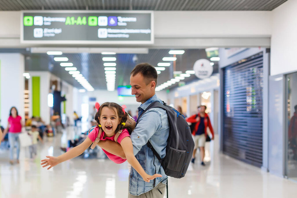 Tatínek objímá dívku na letištní hale se štěstím. - Fotografie, Obrázek
