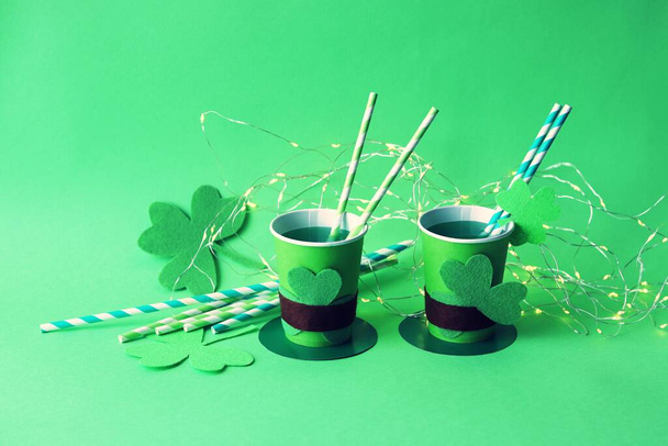 Пийте в паперових чашках у вигляді капелюха Святого Патрика з соломою, сорочкою і освітленням на зеленому тлі, вечірці, вітання, листівки - Фото, зображення