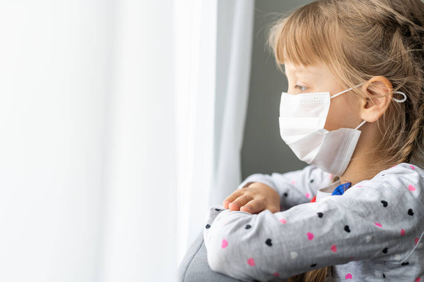 コロナウイルスの流行の間に医療マスクの白人病の少女は祈る - 写真・画像
