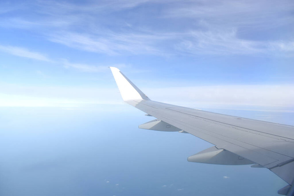 Gyönyörű horizont kék ég fehér repülő szárnnyal a levegőben. Kilátás a repülőgép ablakából - Fotó, kép