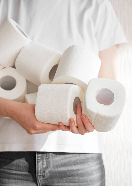 Woman holds many rolls of toilet paper representing panic buying during the coronavirus COVID-19 pandemic in 2020. preparation for quarantine and economic crisis due to coronavirus. Hygiene concept. - Fotoğraf, Görsel