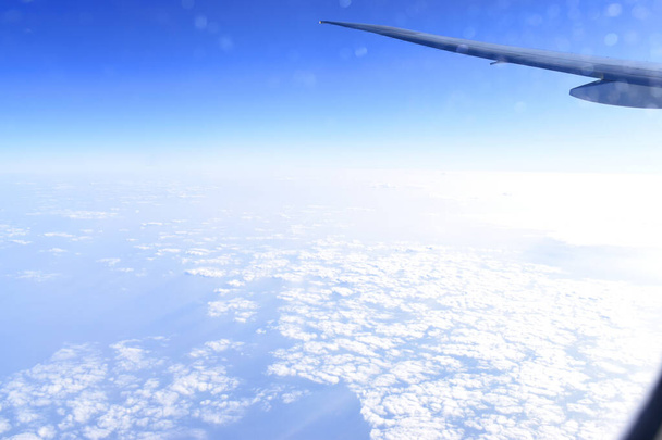 空に飛行機の翼を持つ美しい水平線の青い空。飛行機の窓から見える. - 写真・画像