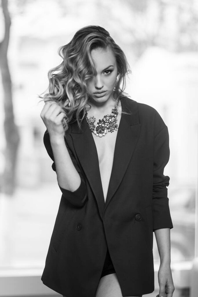 Nahaufnahme Porträt einer sexy jungen Frau im schwarzen klassischen Anzug. Schwarz-Weiß-Foto. Blick in die Kamera. - Foto, Bild