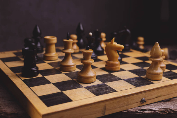 Chess Pieces on the old Chessboard against black color background. - Foto, Bild