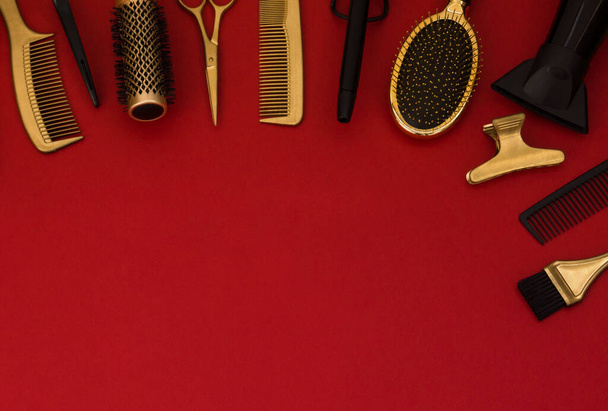 Banner with hairdressing tools. Gold hair salon accessories on red background with space for text. Comb, scissors, hair dryer, brush, brush and hairpins. - Photo, image