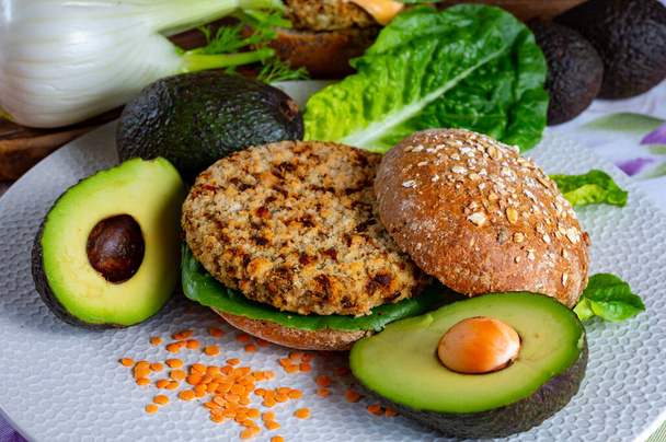 Lezzetli vejetaryen sağlıklı yeşil yemek, portakallı mercimeklerden yapılmış ev yapımı hamburgerler yeşil marul ve taze olgun avokado. - Fotoğraf, Görsel